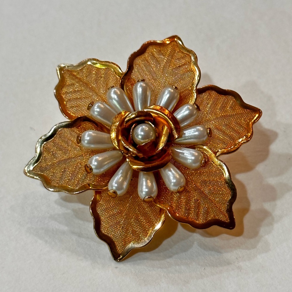 Gold colored flower and pearl brooch.